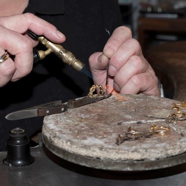 Nærbillede af hænder der arbejder i værksted på en ring.